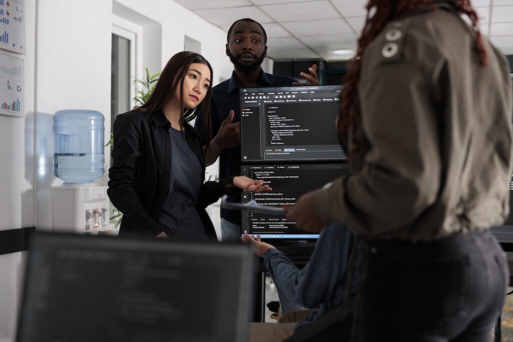 Professionals discuss how to get into IT around a desk.